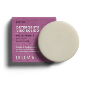 Festes Gesichtsreinigungsprodukt in einer runden Form mit einer lila Verpackung für fahle Haut von Dolomia.