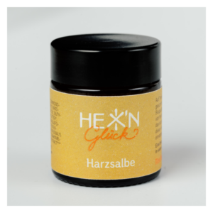Schwarzes Tiegelchen mit gelbem Etikett für Harzsalbe, beschriftet mit "HEX' N Glück".