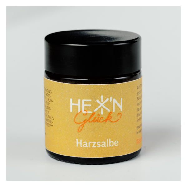 Schwarzes Tiegelchen mit gelbem Etikett für Harzsalbe, beschriftet mit "HEX' N Glück".